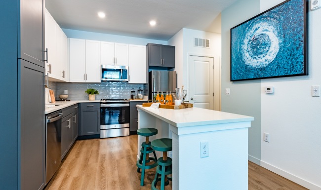 a kitchen with a dining island and chairs at The Shores at Lake Howell Apartments in Casselberry, FL
